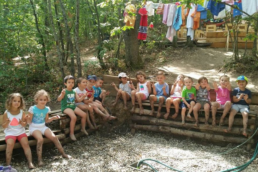 Bambini seduti su una struttura di legno nel bosco